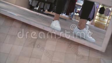 商店里一位年轻女子在镜子旁试穿白色运动鞋